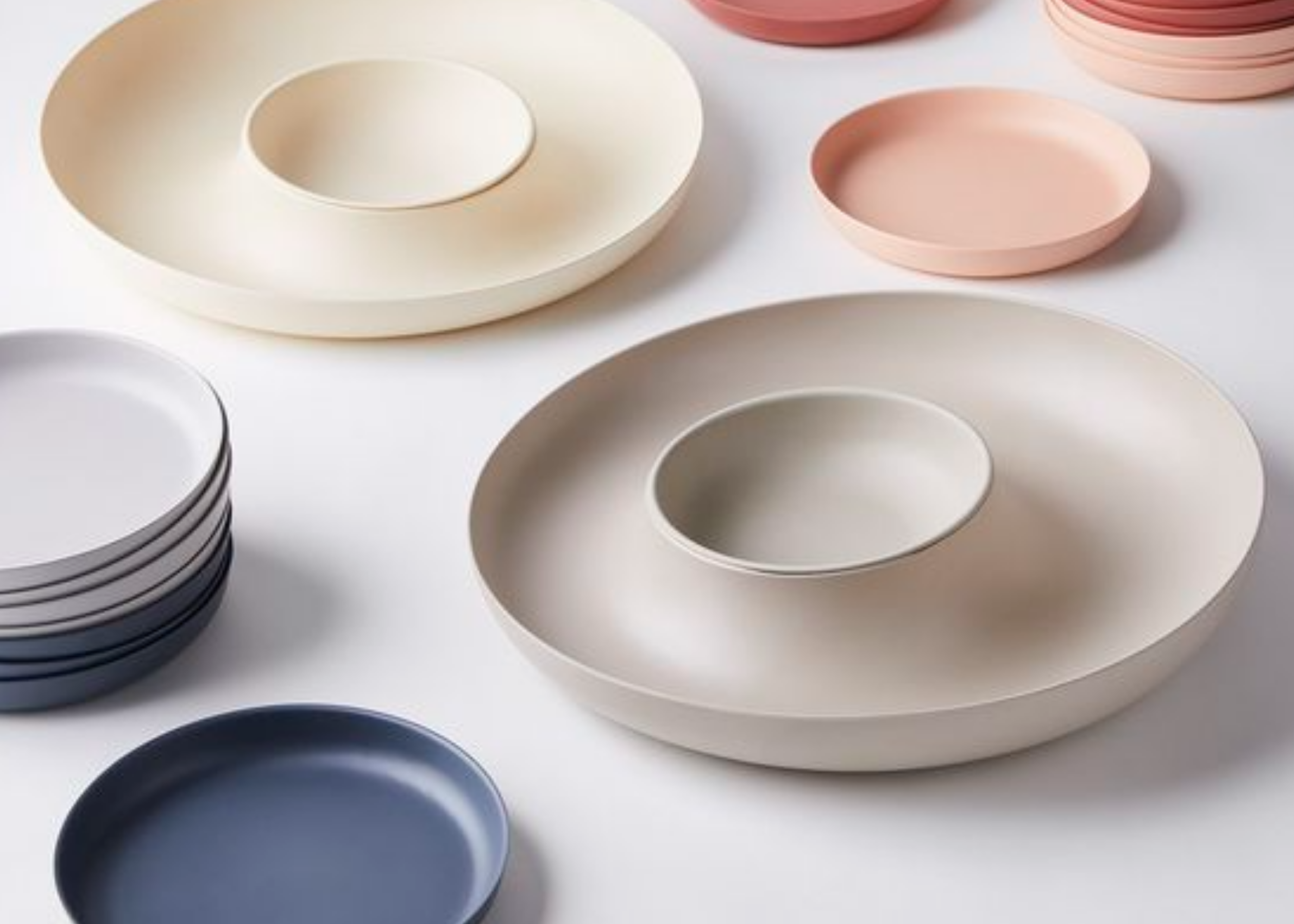 Arranged plates and shallow bowls in neutral and dark colors on a light surface.