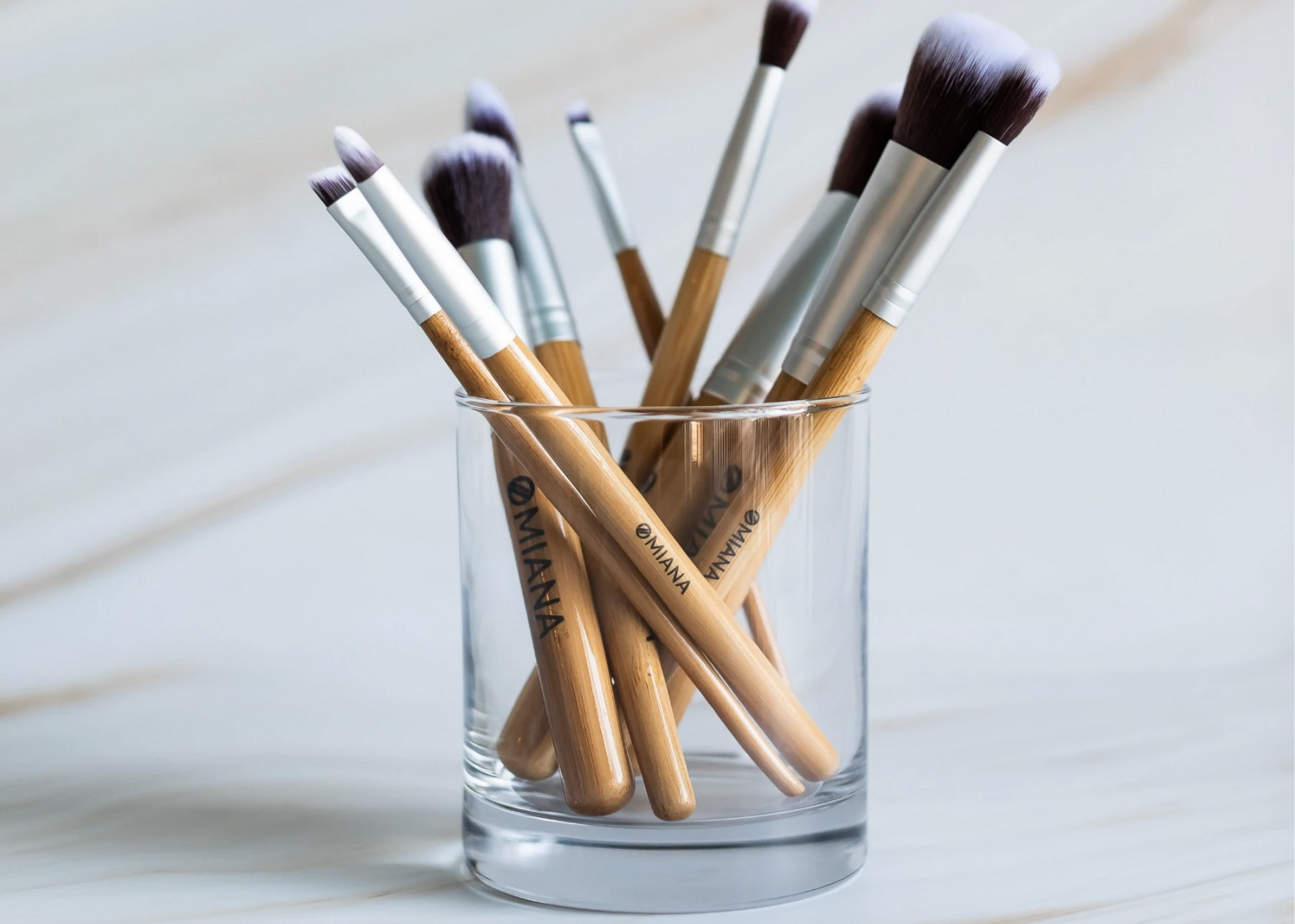 Assorted makeup brushes standing in a clear glass.
