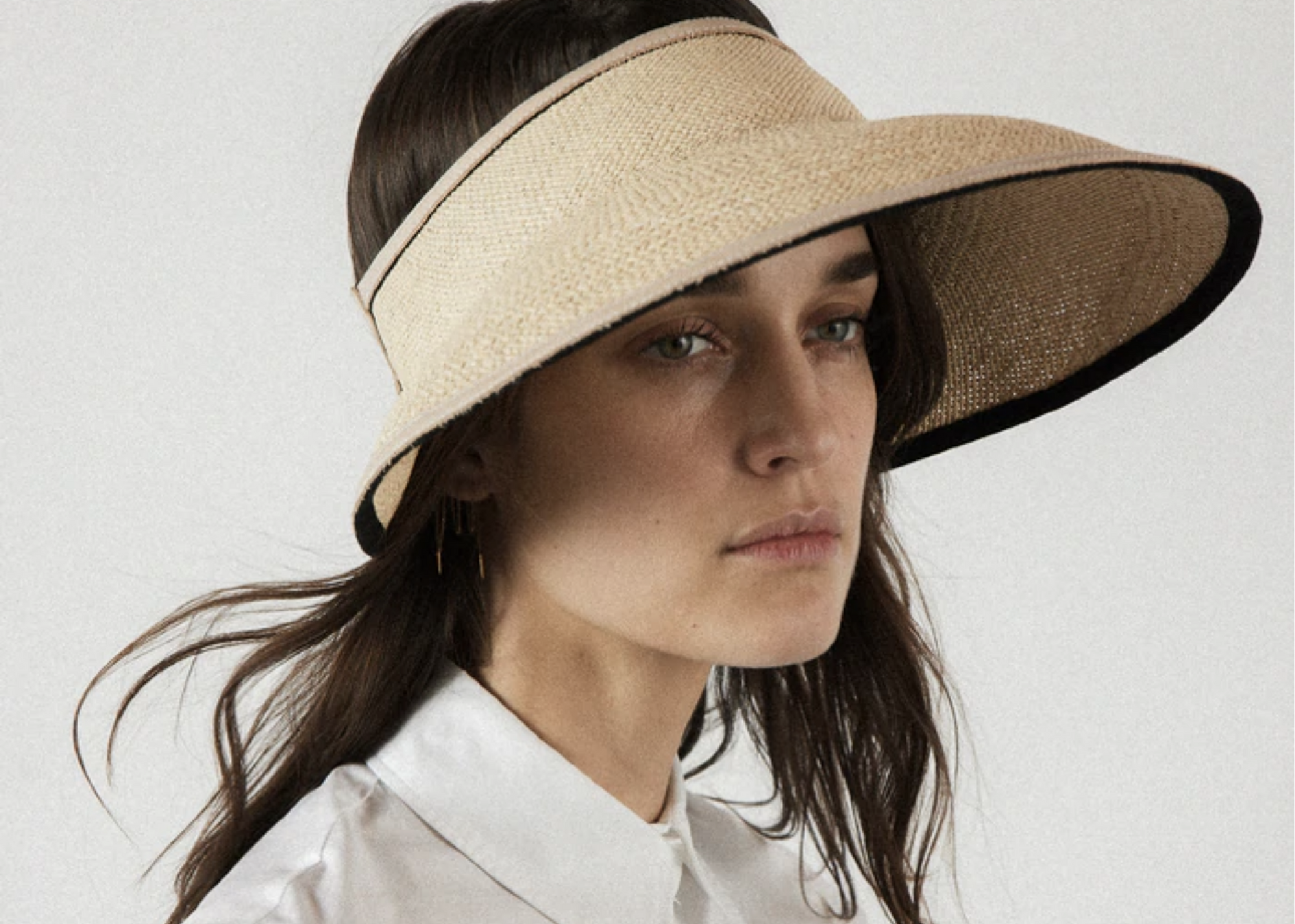 Person wearing a woven visor with a wide brim and a white collared shirt.
