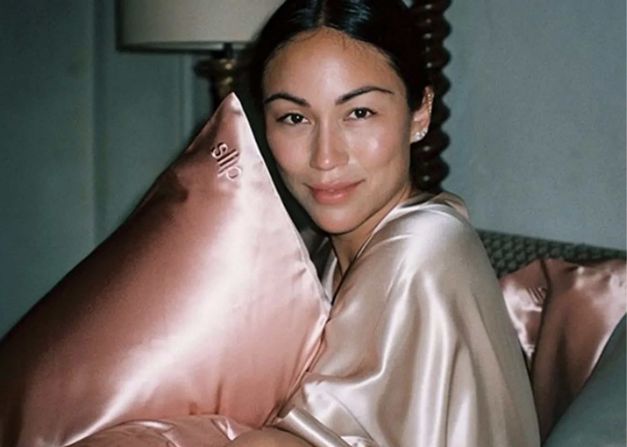 Person in satin sleepwear holding a pink satin pillow labeled Sijo
