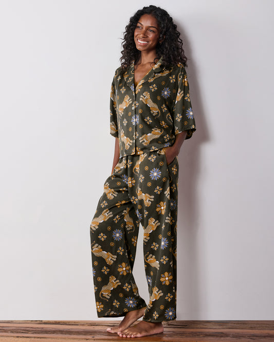 Three-quarter front view of the olive Wildest Dreams pajama set, showing the short-sleeve shirt, wide-leg pants, leopard and flower prints, and a pants pocket.