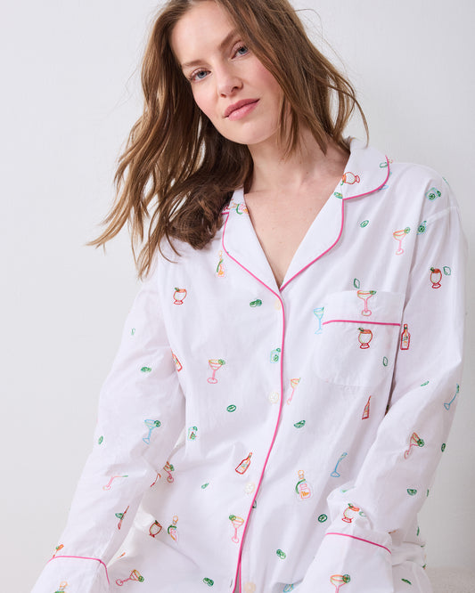 Close-up front view of the long pajama shirt showing its notched collar, chest pocket, pink piping, buttons, and cocktail-themed embroidery.