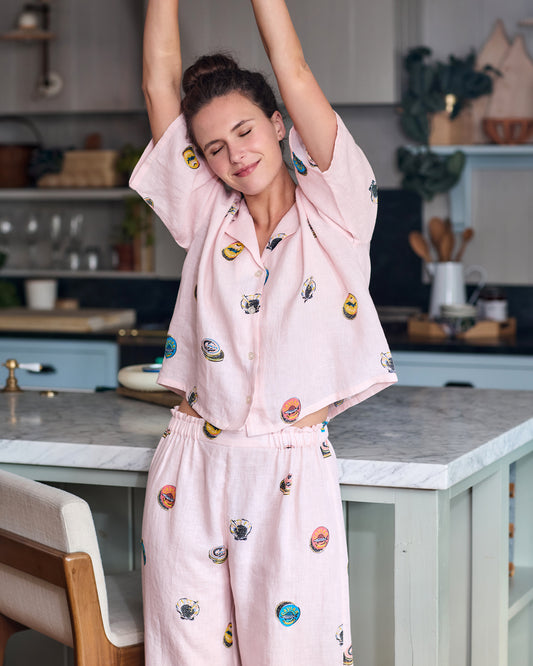 Person wearing the pink pearl cropped top and wide-leg pants set with colorful embroidered caviar-tin motifs in a kitchen.