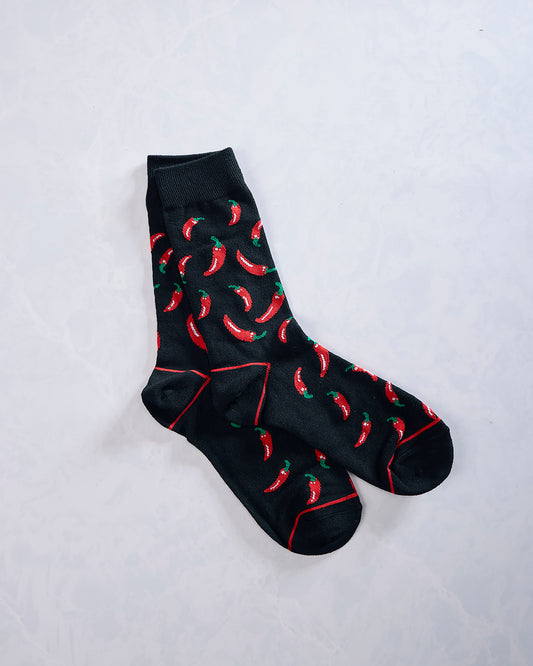 Pair of black crew socks covered in red chili pepper designs, shown crossed on a light background.