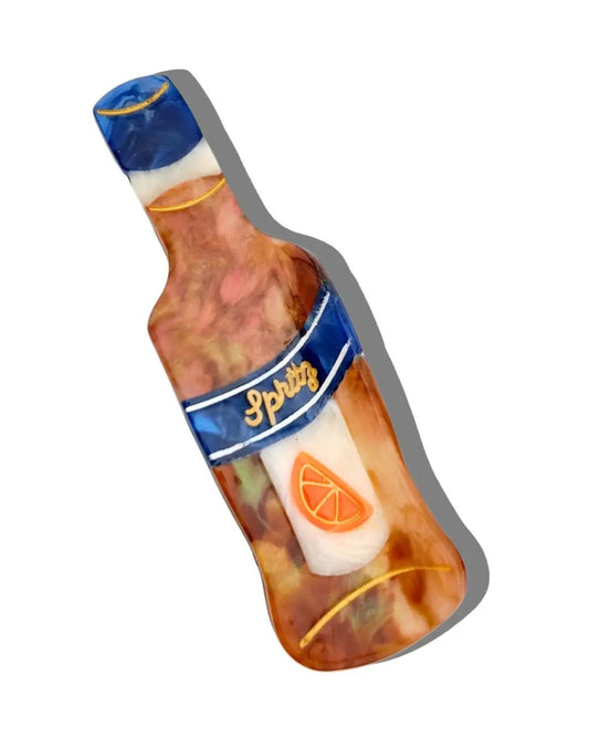 Citrus-themed claw hair clip shaped like a tilted bottle, with an orange slice graphic and blue label.