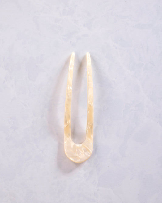 White shell French hair pin shown in full, with two long prongs and a rounded base.